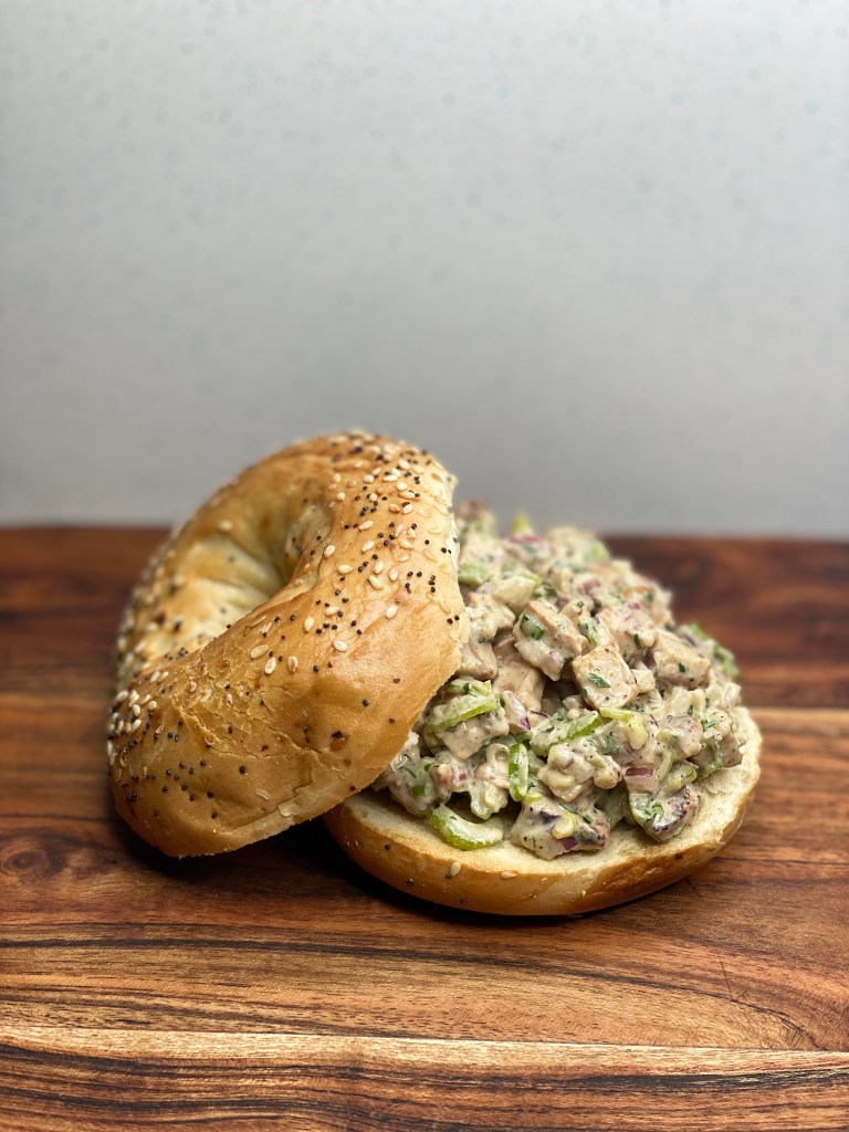 Delicious vegan chicken salad spread on a toasted bagel.